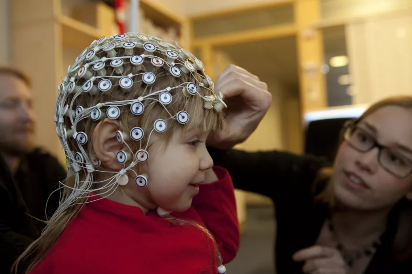 En forskare mäter ett barns hjärnaktivitet. Foto. 